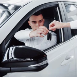 two-men-stand-showroom-against-cars-close-up-sales-manager-suit-that-sells-car-customer-seller-gives-key-customer_146671-14744